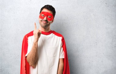 Süper kahraman adam ile gösterilen ve dokulu gri arka plan üzerinde en iyi işareti parmak kaldırma maskesi ve kırmızı pelerin