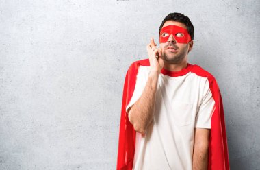 Süper kahraman maske ve kırmızı pelerin ile en iyi dilek ve geçiş parmak adamla. Bir dilek yapma. gri arka plan üzerinde dokulu