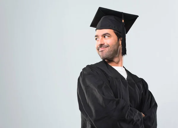灰色の背景に笑みを浮かべて肩を見ながら側臥位に彼の卒業日の大学の男 — ストック写真