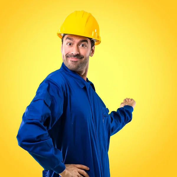 제품을 노란색 바탕에 손가락으로 가리키는 노동자 — 스톡 사진