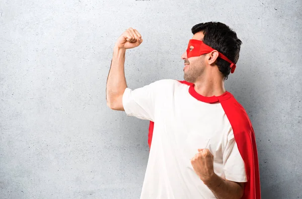 質感の灰色の背景上の勝者の位置の勝利を祝ってマスクと赤のケープとスーパー ヒーローの男 — ストック写真