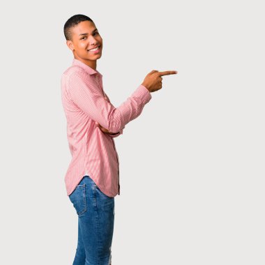 Parmak tarafına işaret ve gri arka plan üzerinde lateral pozisyonda bir ürün sunma genç Afro-Amerikan adam