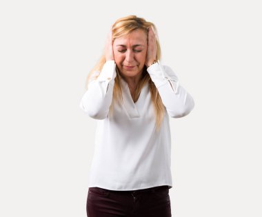 Orta yaş beyaz gömlek her iki kulak elleriyle kapsayan sarışın kadınla. Hayal kırıklığı ifade izole gri arka plan üzerinde