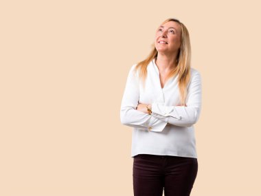 Beyaz gömlek stand ve izole koyu sarı arka plan üzerinde gülümseyen ararken orta yaş sarışın kadınla