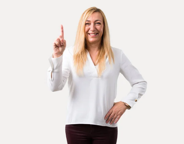 中年金发女人白衬衫显示和举起手指在一个最好的在孤立的灰色背景的标志 — 图库照片