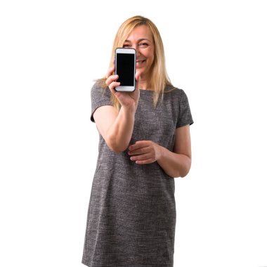 Kameraya bakarak ve izole beyaz arka plan üzerinde mobil kullanırken gülümseyen orta yaş sarışın kadın