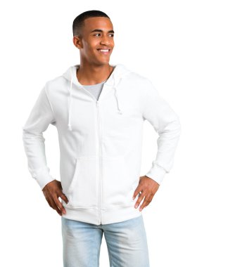 Genç adam koyu tenli arms adlı kalça ile poz gülen ve izole beyaz arka plan üzerinde beyaz kazak ile