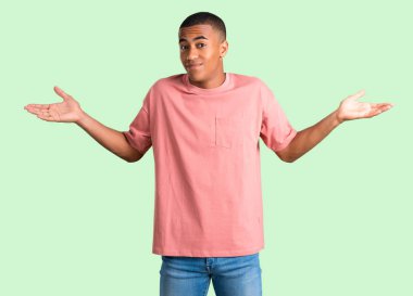 Karanlık adam önemsiz hale derili ve omuz ve ellerde yeşil izole arka plan üzerinde kaldırma sırasında jest şüpheler