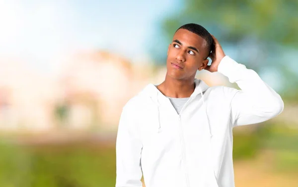 Μελαχροινός Νεαρός Άσπρη Μπλούζα Στέκεται Και Σκέφτεται Μια Ιδέα Ενώ — Φωτογραφία Αρχείου
