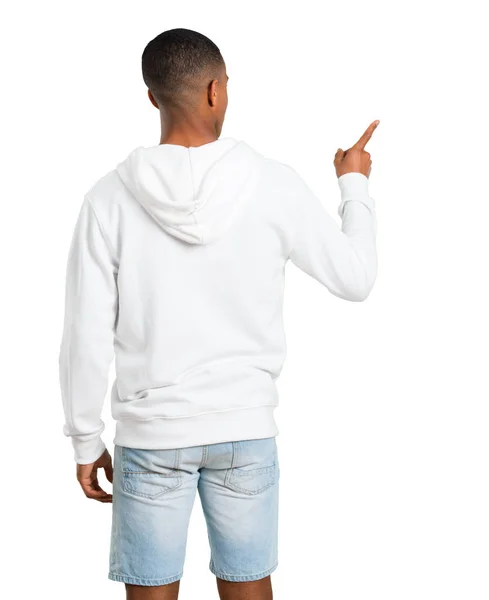 深色皮肤的年轻男子与白色运动衫指向背面的食指在孤立的白色背景 — 图库照片