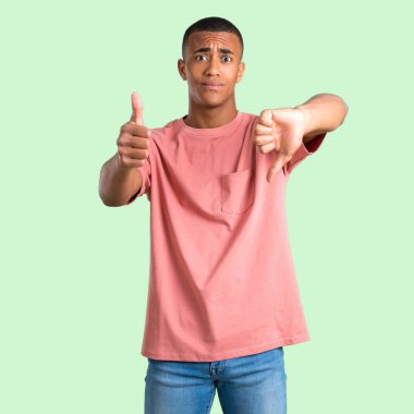 İyi-kötü işaret yapma adam koyu tenli. Kararsız kişi Evet arasında veya değil yeşil izole arka