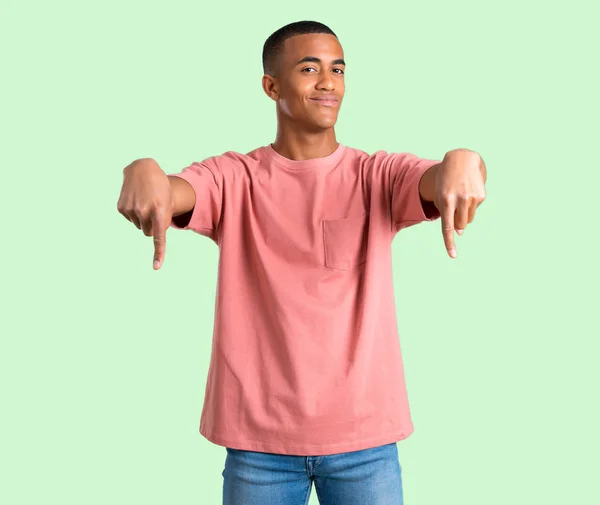 Темношкірий Чоловік Вказує Вниз Пальцями Зеленому Ізольованому Фоні — стокове фото
