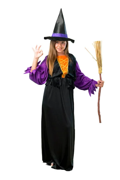一个小女孩的一个完整的镜头打扮成一个女巫万圣节假期显示一个 标志与手指隔离在白色 — 图库照片