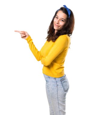 Sarı kazak ve parmak tarafına işaret ve bir ürün yalıtılmış beyaz arka planda lateral pozisyonda sunma başında mavi bandana ile genç kız