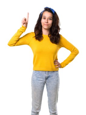 Sarı kazak ve başında gösterilen ve işareti en iyi izole beyaz zemin üzerinde bir parmak kaldırma mavi bandana ile genç kız