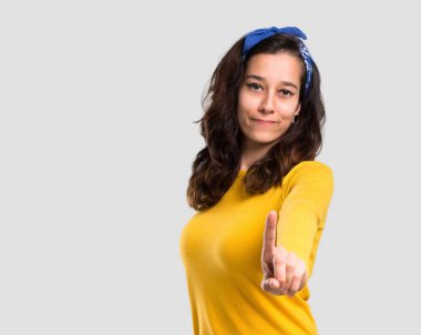 Sarı kazak ve başında gösterilen ve işareti en iyi izole gri arka plan üzerinde parmak kaldırma mavi bandana ile genç kız