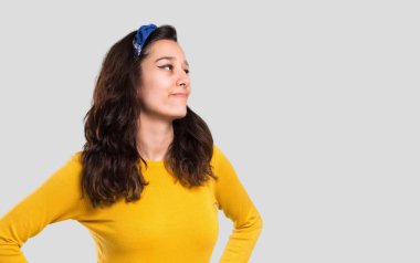 Sarı kazak ve kalça, silah ile poz ve izole gri arka plan üzerinde gülüyor başında mavi bandana ile genç kız