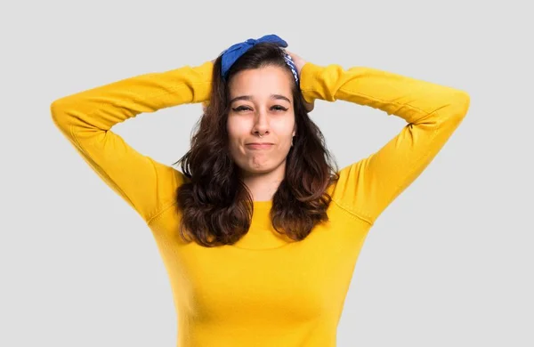 黄色いセーターを着て 頭に青いバンダナを持つ少女は のでの頭の上の手を取る片頭痛は 孤立した灰色の背景 — ストック写真