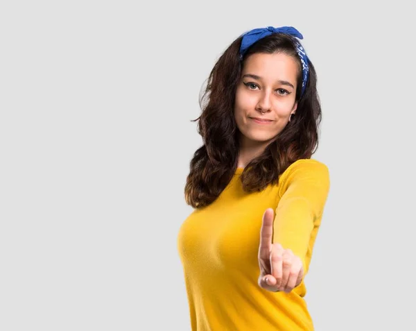 年轻女孩与黄色毛衣和蓝色头巾在她的头上显示和举起手指在查出的灰色背景最好的标志 — 图库照片