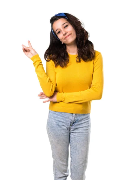 黄色いセーターを着て 青いバンダナ分離の白い背景の上の陽気な顔と勝利のサインを示し笑みを浮かべて彼女の頭の上の少女 — ストック写真