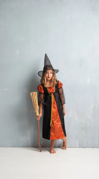 Malá dívka oblečená jako čarodějnice a drží koště na halloween — Stock fotografie