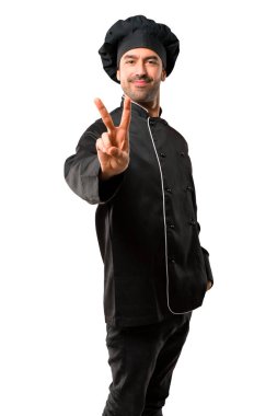 Şef adam siyah üniforma gülümseyen ve gösteren zafer izole beyaz arka plan üzerinde oturum