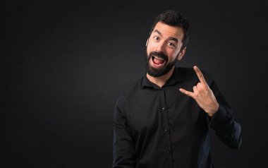 Siyah arka plan üzerine sakal yapma rock hareketi ile yakışıklı adam