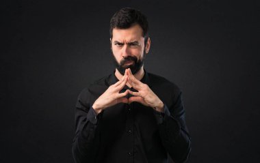 Siyah arka plan üzerine şüpheleri sakallı yakışıklı adam