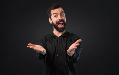 Siyah arka plan üzerine bir şey sunmak sakallı yakışıklı adam