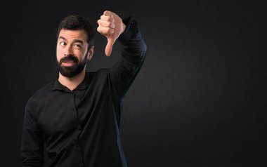 Siyah arka plan üzerine kötü sinyal yapma sakallı yakışıklı adam