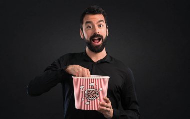 Popcorns siyah arka plan üzerine yemek sakallı yakışıklı adam