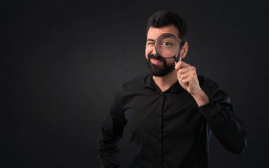 Siyah arka plan üzerine büyüteç ile sakallı yakışıklı adam