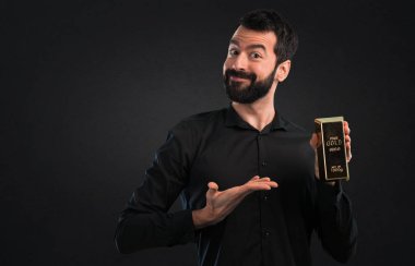 Siyah zemin üzerine altın külçe ile sakallı yakışıklı adam