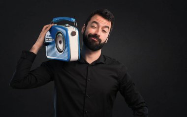 Siyah arka plan üzerine bir radyo tutan sakallı yakışıklı adam