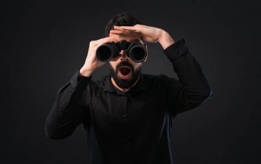 Siyah arka plan üzerine dürbünlü sakallı yakışıklı adam