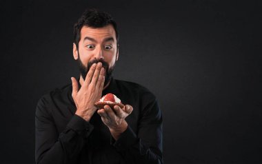 Siyah arka plan üzerine pasta ile sakallı yakışıklı adam