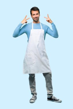 Tam vücut dilini komik göz mavi arka plan üzerinde olan kamera gösterilen bir önlük giyen adam