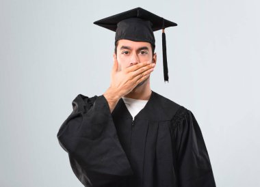 Uygunsuz bir şey söylediğin için el ile ağız kapsayan onun mezuniyet günü üniversite adamı. Gri arka plan üzerine konuşamam