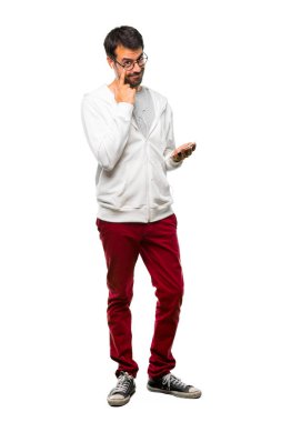 Bir adam gözlük ve ayakta ve beyaz zemin üzerine parmağınızla göz açılış açık isteyen müzik dinleme tam uzunlukta bir kadeh