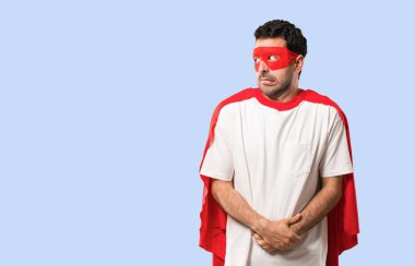 Süper kahraman maske ve kırmızı pelerin biraz gergin ve korkmuş diş izole mavi zemin üzerine basarak adam