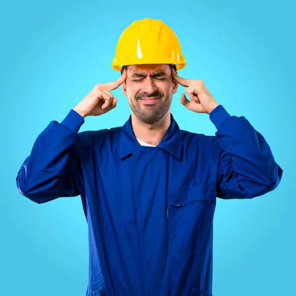 ヘルメット不幸とものに不満を持つ若い労働者は 青の背景に否定的な表情 — ストック写真
