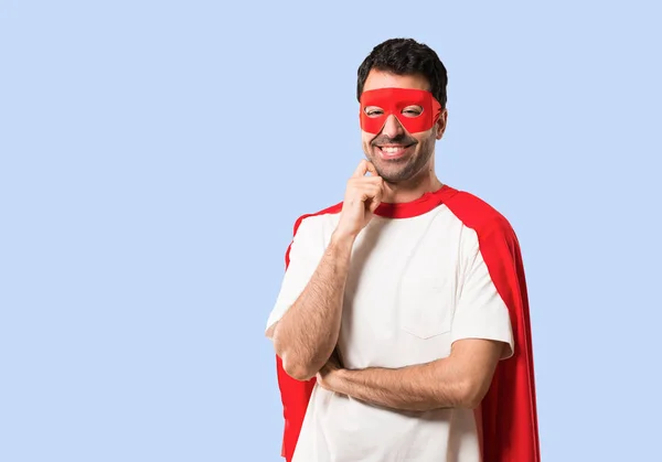 スーパー ヒーロー マスクと赤マントは分離の青い背景に甘い表情で笑みを浮かべて男 — ストック写真