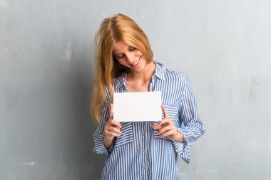 Sarışın kız boş bir afişini dokulu grunge duvar arka planda tutan