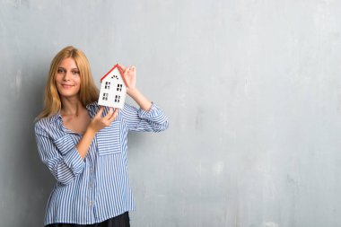 Sarışın kız dokulu grunge duvar arka plan küçük bir ev tutarak