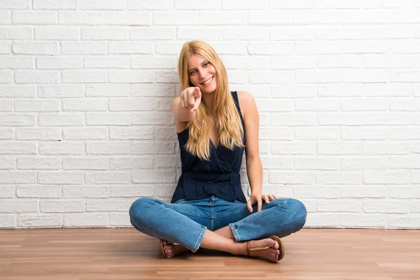 Blond Meisje Zittend Vloer Vinger Naar Wijst Witte Bakstenen Muur — Stockfoto