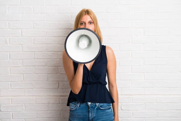 Blond Meisje Houdt Een Megafoon Witte Bakstenen Muur Achtergrond — Stockfoto