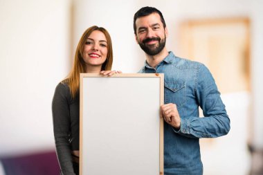 Adam ve boş bir afişini odaklanmamış arka planda tutan kadın