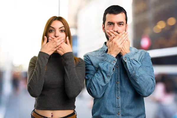 Man and woman covering their mouths on unfocused background