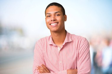 Afro-Amerikan delikanlı odaklanmamış açık arka plan üzerinde gülümseyen süre geçti silah tutmak