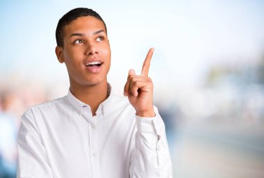 Parmak odaklanmamış açık arka plan üzerinde kaldırma sırasında çözüm isteyen genç Afro-Amerikan adam anlar